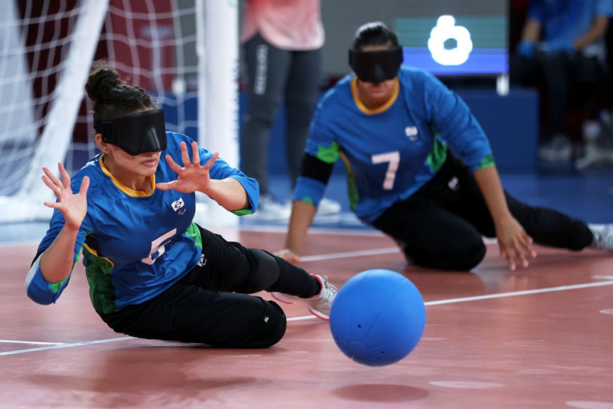 A female athlete tries to block a ball in front of the goalball net